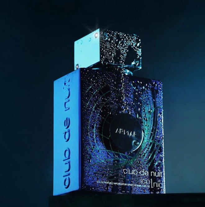 Blue eau de parfum bottle with cap shown with product box in dark background