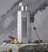 Eau de Parfum bottle with silver cap, textured gray glass, and lavender sprig
