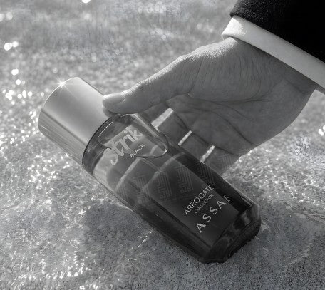 Hand holding black EDP spray bottle with silver cap and 'Strike' label
