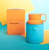 Eau de parfum bottle with orange cap, teal body and handle; includes matching box