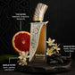 Perfume bottle with metallic cap, amber liquid, with grapefruit, flowers, and spices.