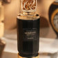 Black perfume extrait bottle with gold crown cap and gold band, front label detail