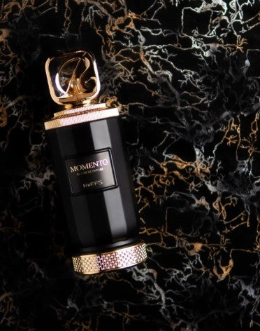 Black perfume extrait bottle with gold cap, gold logo label, and textured base ring