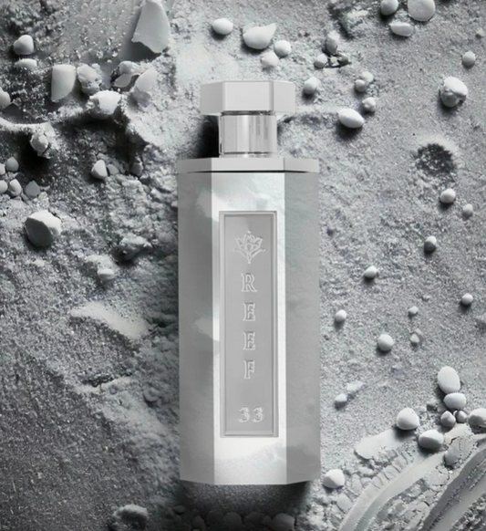 White frosted perfume bottle with silver cap and 'REEF 33' label