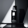 Black eau de parfum bottle with faceted top, UNE label on stand