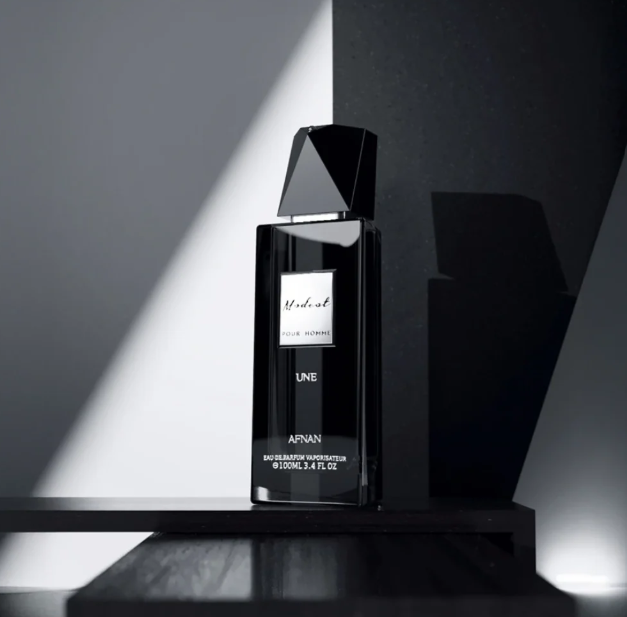 Black eau de parfum bottle with faceted top, UNE label on stand