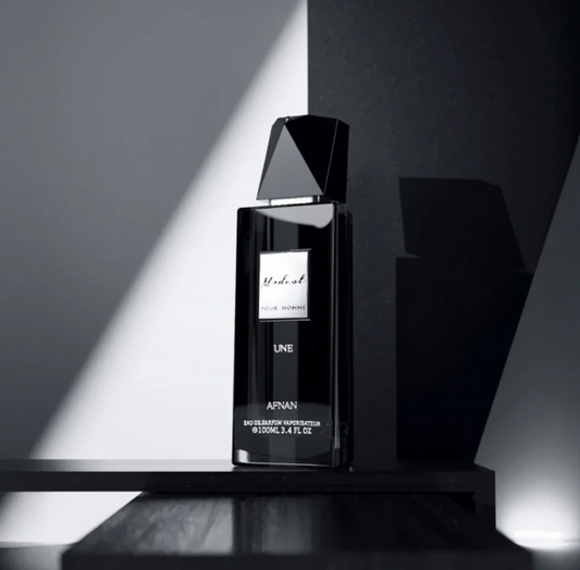 Black eau de parfum bottle with faceted top, UNE label on stand