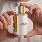 Perfume bottle held in hands, gold cap and white label with Dulook text